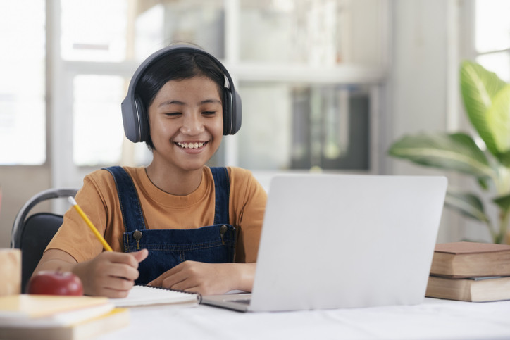 girl doing homework on computer in kitchen